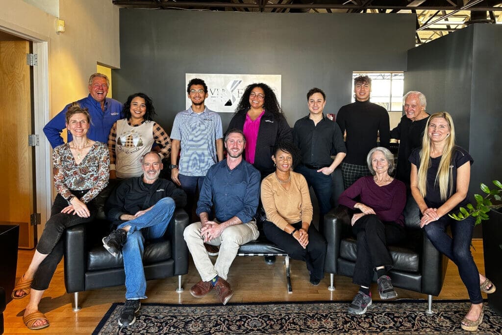 A large team of 13 people sitting and standing together at Seaver Franks architectural design firm